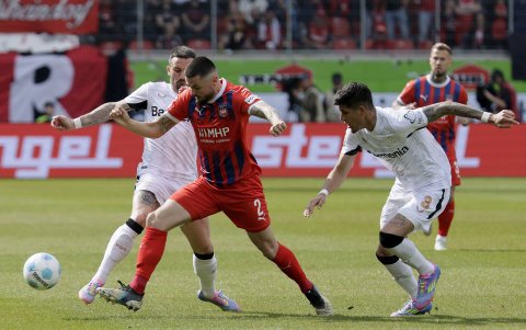 Marnon Busch de Heidenheim (C) reacciona ante el acoso de Aleix Garcia (i) y el ecuatoriano Piero Hincapie del Leverkusen (R) durante el cotejo de Bundesiga.