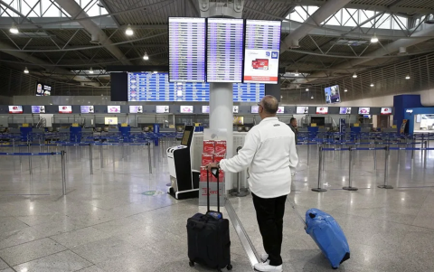 Un pasajero mira a la lista de vuelos de un aeropuerto griego, en el marco de huelgas masivas que paralizan al país.