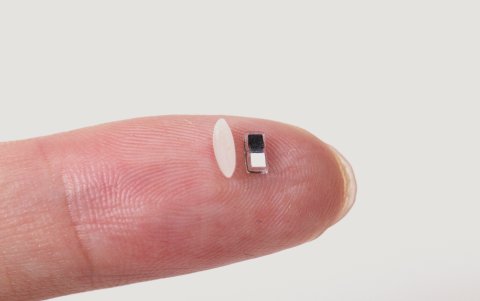 El prototipo experimental de marcapasos junto a un grano de arroz en la yema de un dedo.