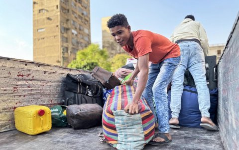 Refugiados sudaneses descargan su equipaje en un punto de reunión para los autobuses organizados para su regreso voluntario de Egipto a Sudán.