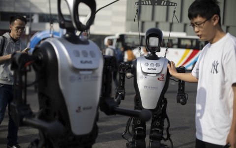 Un técnico observa un robot humanoide antes de una carrera entre humanos y robots en Pekín.