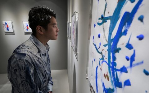 Dan Isomura, director de la galería, posando con la obra de arte abstracta exhibida por el artista 