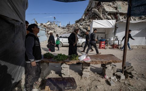 Palestinos desplazados se reúnen en un mercado cerca de los escombros de edificios destruidos en Jabalia, al norte de la Franja de Gaza, el 27 de abril de 2025.