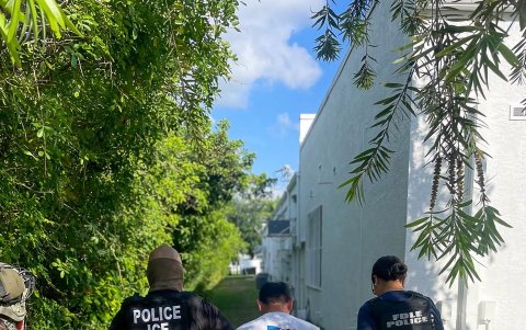 Uno de sus agentes (i) y un policía de Florida (d) mientras llevan a un indocumentado arrestado en Florida (Estados Unidos).