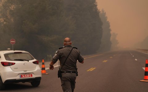 Un elemento de seguridad camina por una carretera aledaña a la zona de los incendios próximos a Jerusalén.