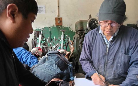 Uno de los colaboradores aplica pegamento en la suela de un zapato deteriorado.