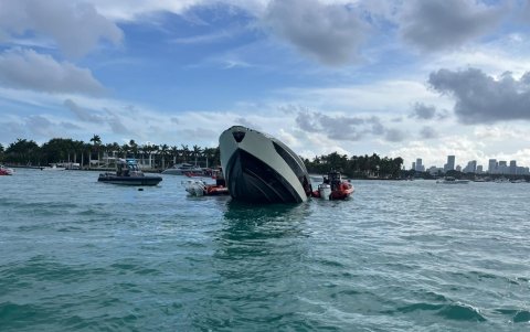 Foto de la cuenta oficial de la red social X del Séptimo Distrito de la Guardia Costera de Estados Unidos (USCG, en inglés) que muestra un yate semihundido con personas a bordo, frente a Miami Beach.