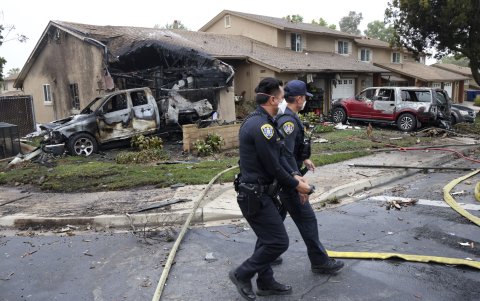 Agentes de policía registran el lugar donde una avioneta se estrelló en una calle residencial de San Diego, California, el 22 de mayo de 2025.