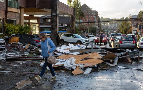 Una mujer camina junto a los destrozos causados que dejó un tornado este domingo, en la ciudad de Puerto Varas (Chile).