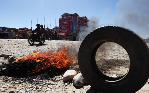 Unas personas transitan junto a una vía bloqueada durante una protesta este martes, en El Alto (Bolivia).