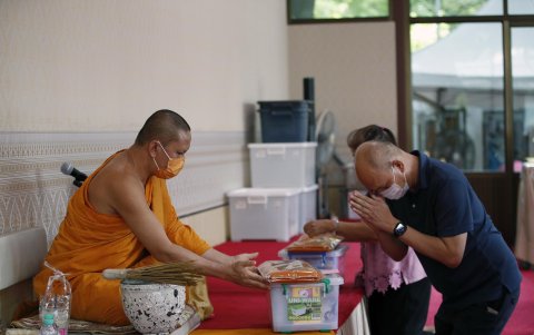 Un monje budista tailandés (izq.) usa una máscara facial durante un rito en un templo en Bangkok, Tailandia, el 20 de mayo de 2025.