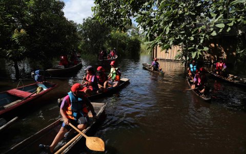 Un grupo de niños en canoas dirigiéndose a un vivero por el rio Itaya, en Iquitos (Perú).
