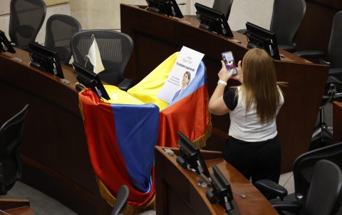 Una mujer toma una fotografía de la curúl del senador Miguel Uribe Turbay cubierta con la bandera de Colombia este lunes, en Bogotá (Colombia).