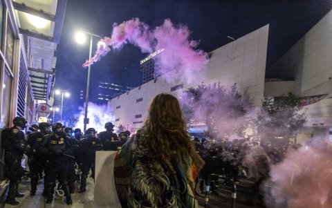 Una bomba de humo se arquea sobre una línea policial durante una manifestación tras las operaciones federales de inmigración en Los Ángeles el 9 de junio de 2025.