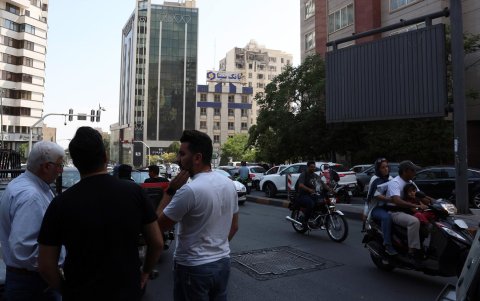 Los espectadores se reúnen cerca de un edificio dañado que fue alcanzado por ataques aéreos israelíes, al norte de Teherán, Irán, el 13 de junio de 2025.