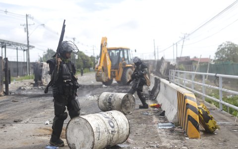 Integrantes de la Unidad de Control de Multitudes (UCM) observan una vía bloqueada en la jornada de protestas esté domingo, en Changuinola, Bocas del Toro, (Panamá).