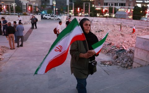 Una mujer iraní con banderas nacionales escucha a una banda de música tradicional que toca en solidaridad con el pueblo iraní en la plaza Hafte-Tir, en el centro de Teherán, Irán, el 23 de junio de 2025.