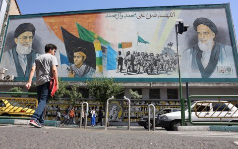 Iraníes caminan junto a una pintura mural del líder supremo iraní, el ayatolá Ali Jameneí (arriba-i) y el fallecido líder supremo iraní, el ayatolá Ruhollah Jomeiní, en una calle de Teherán.