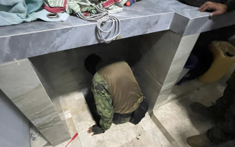 Un militar inspecciona el compartimento oculto bajo una baldosa donde se escondía alias Fito. El acceso estaba camuflado con cobijas y objetos domésticos en una vivienda de Manta.