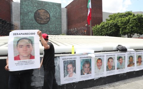 Familiares y colectivos de personas desaparecidas colocan carteles con fotografías durante una protesta este miércoles al exterior de la Cámara de Diputados en la Ciudad de México (México).