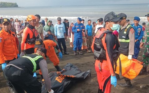 Rescatistas llevando a una víctima en una bolsa para cadáveres, luego de que un ferry volcara en las aguas del estrecho de Bali en Ketapang.