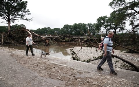 Itchell y Sarah Roeder observan los daños causados ​​por las inundaciones con su hija Madelyn y su perro Arlo, en Kerrville, Texas, EE. UU.