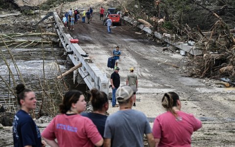 La gente observa cómo las fuerzas del orden y voluntarios buscan personas desaparecidas cerca de Camp Mystic, tras las inundaciones repentinas en Hunt.