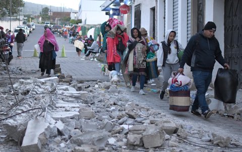 Personas caminan este miércoles cerca de los escombros ocasionados tras los fuertes temblores, en Palín (Guatemala).