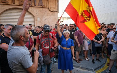 Una mujer con una bandera de España con el sagrado corazón de Jesús.
