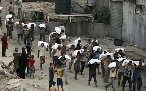 Hombres caminan cargando sacos de harina que fueron robados de un camión que transportaba alimentos, en Khan Yunis, en el sur de la Franja de Gaza, el 22 de julio de 2025.