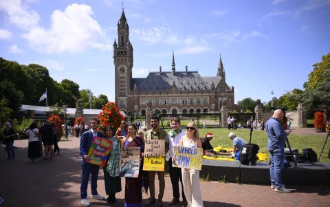 Líderes ambientalistas posan con carteles antes de la sesión de la Corte Internacional de Justicia (CIJ) sobre las obligaciones legales de los Estados para abordar el cambio climático, en La Haya.