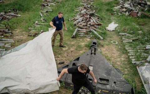 Dmytro Chubenko, portavoz del fiscal de Járkov, y su asistente cubren un dron ruso Shahid derribado por fuerzas de defensa aérea en un campo destinado al almacenamiento de misiles rusos en Járkov.