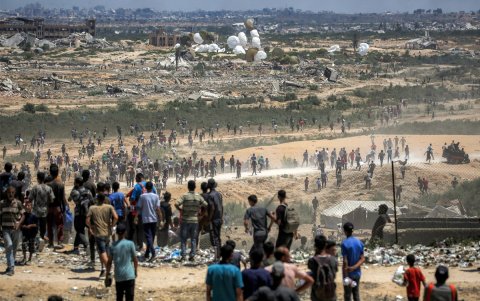 Los palestinos acuden al lugar mientras paletas aéreas que transportan ayuda humanitaria caen en paracaídas tras ser arrojadas desde un avión militar.