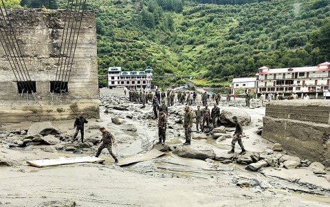 Personal de seguridad y socorro construyen un cruce sobre un arroyo de lodo denso durante una operación de búsqueda y rescate, un día después del deslizamiento de tierra masivo.