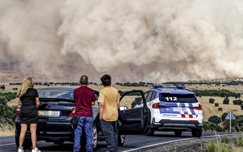Un grupo de personas paradas en la carretera AV-500, la cual se encuentra cortada en las proximidades de Urraca-Miguel, barrio anexionado de Ávila capital con motivo del incendio.