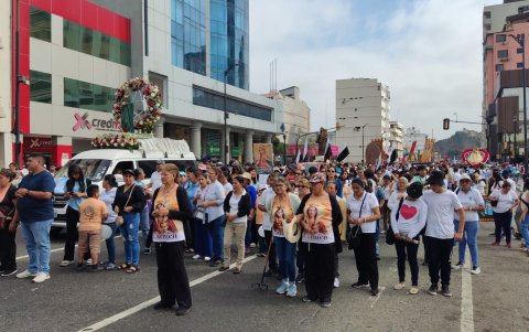 Devotos rezan el rosario mientras acompañan la procesión en honor a la Virgen María, en el centro de Guayaquil.