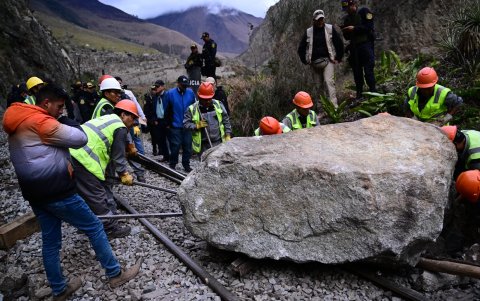 Los trabajadores intentan retirar una piedra colocada por los alborotadores en la vía del tren para bloquear el paso del tren hacia y desde la ciudadela inca de Machu Picchu.