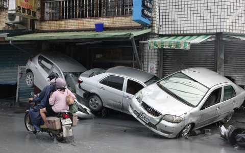 Los residentes viajan en motocicleta junto a automóviles dañados, arrastrados por las aguas de la inundación, en Hualien el 24 de septiembre de 2025.