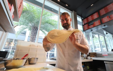 Diego enseña que la verdadera pizza italiana se estira a mano, no con rodillo.