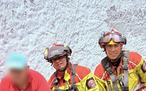 El tutor de Garú sujeta a su perro, luego de que los bomberos lo rescataron del fondo de la quebrada.