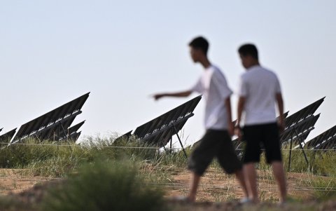 Personas caminan junto a paneles solares en la estación fotovoltaica Dalat Banner, también conocida como la estación Caballo fino, en el desierto de Kubuqi, cerca de Ordos.