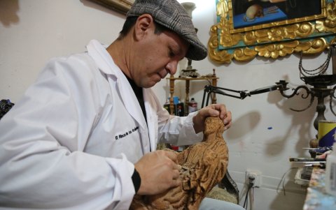 El artista y restaurador limpia y talla con precisión una pieza de madera muy antigua.