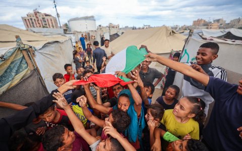 Niños palestinos celebran en un campamento para desplazados en Nuseirat, en el centro de la Franja de Gaza, el 9 de octubre de 2025, tras la noticia de un nuevo acuerdo de alto el fuego en Gaza.