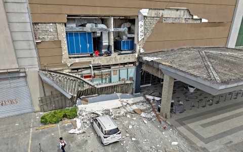 Un guardia de seguridad pasa junto a una pared dañada y un automóvil afuera de un centro comercial en la ciudad de Butuan, en la isla sureña de Mindanao, el 10 de octubre de 2025.