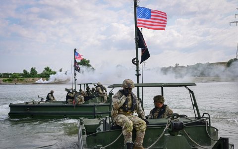Soldados estadounidenses operan embarcaciones de empuje que se utilizarán para el ensamblaje y operan una barcaza de transporte a través del río Danubio.