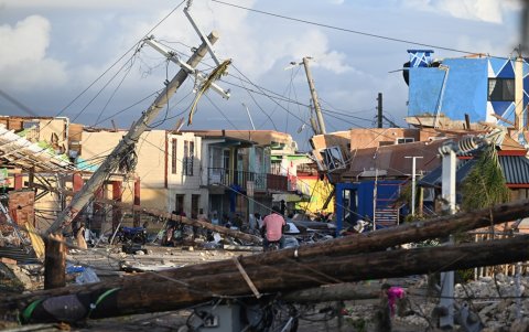 Postes eléctricos caídos mientras un hombre recorre en bicicleta el vecindario destruido de North Street tras el paso del huracán Melissa, en Black River, Jamaica, el 29 de octubre de 2025.