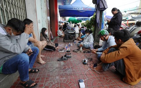 Personas cargan sus teléfonos en un área pública tras los cortes de energía provocados por el tifón Kalmaegi en Vietnam, 7 de noviembre de 2025.