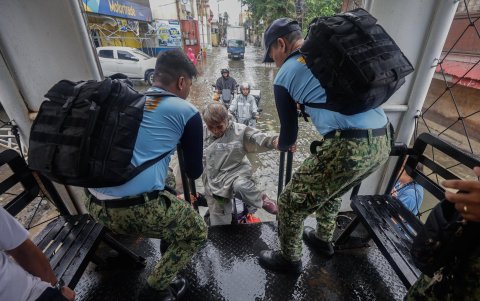 Policías filipinos desde un camión que ofrece transporte gratuito ayudan a un residente en un distrito inundado el 10 de noviembre de 2025.