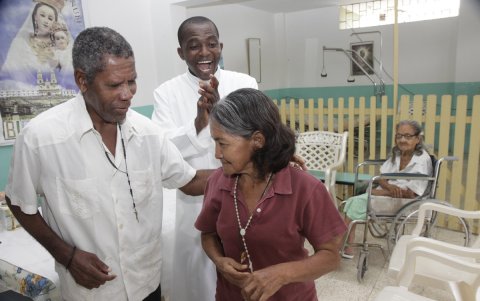 El padre ghanés John Cudjoe anima a danzar a dos personas. La imagen corresponde al año 2012.