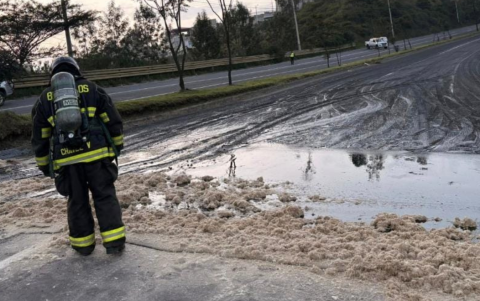 Personal del Cuerpo de Bomberos de Quito realiza la limpieza de la brea derramada tras el volcamiento de un tanquero en el redondel de Gualo.